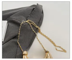 Close-up of golden metal chain strap with oval rings on a gray suit jacket