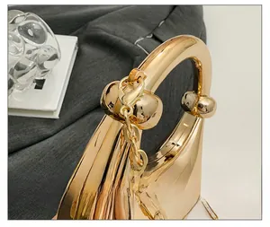 Detailed close-up of polished gold handbag showing metal texture and chain linkage