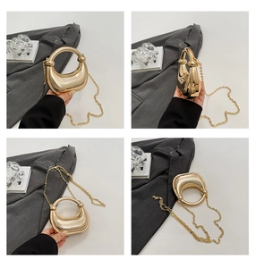 Detail view of gold crescent handbag with circular handle and sleek mirror finish