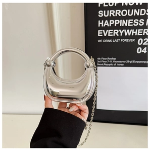 Close-up of mini silver mirror handbag with crescent shape and metal chain strap