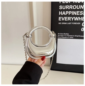 Macro detail of a mini silver crescent handbag with a round handle and chain strap