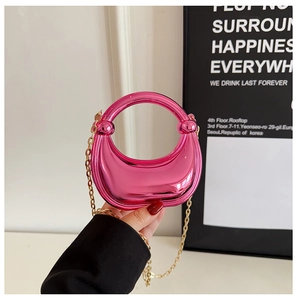 Detail of metallic pink crescent handbag with round handle and gold chain shoulder strap