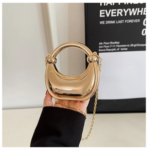 Close-up of golden crescent bag with mirror finish and elegant metal chain strap