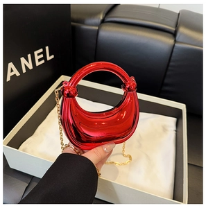 Detail of red crescent bag with mirror finish and elegant gold chain strap