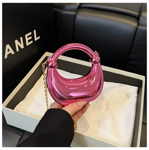 Macro detail of metallic pink crescent handbag with spherical accents and gold chain strap
