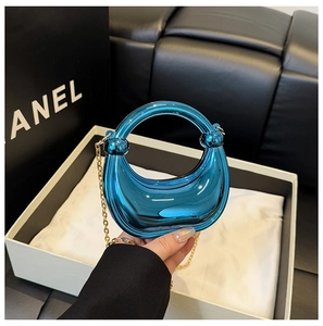 Detail of blue mirror finish crescent handbag with gold chain and round handle
