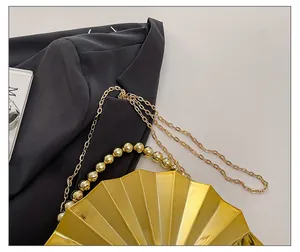 Detailansicht einer fächerförmigen goldenen Abendtasche mit Perlengriff und Metallkette