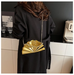 Detail der fächerförmigen goldenen Abendtasche mit Metallstruktur an der Schulter des Models