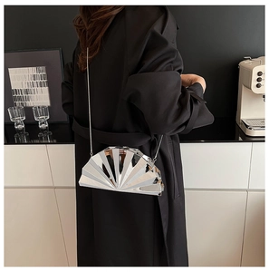 Detailsicht einer silbernen fächerförmigen Abendtasche mit Kette auf schwarzem Mantel