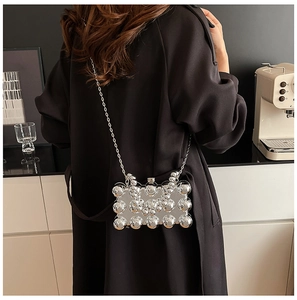 Close-up of a silver chain bag featuring reflective sphere embellishments in a modern setting