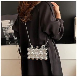 Detail view of a silver metallic crossbody bag with 3D sphere decor and chain strap