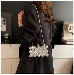 Detail of silver metallic bubble clutch with sleek chain strap over a black coat