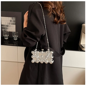Close-up of a silver clutch bag featuring 3D spherical studs and a sleek metal chain strap