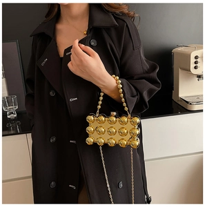 Detailed view of a gold hard-shell mini bag with 3D beads and metallic chain strap