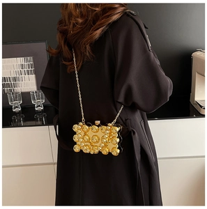 Close-up of golden evening bag with 3D sphere textures and elegant metal chain strap