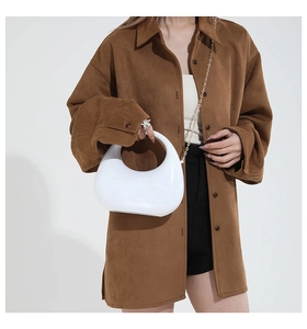 Minimalist white semi-circular acrylic clutch with gold chain strap worn on brown outfit