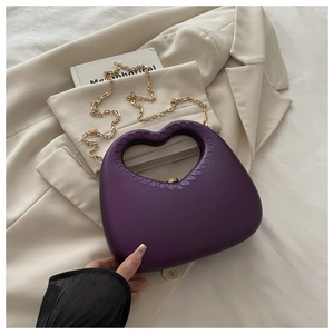 Detail of deep purple heart-shaped handle and matte texture on elegant evening clutch bag