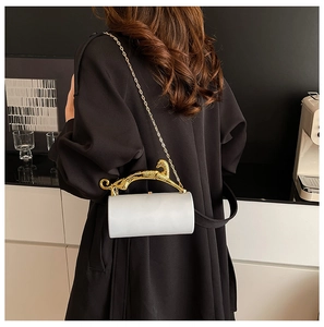 Detail of white cylinder evening bag featuring a gold leopard-shaped metal handle