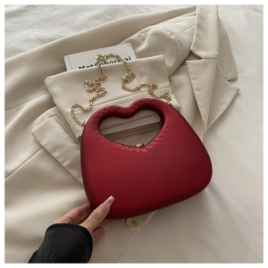 Detail view of heart-shaped clutch bag with matte red finish and gold chain strap