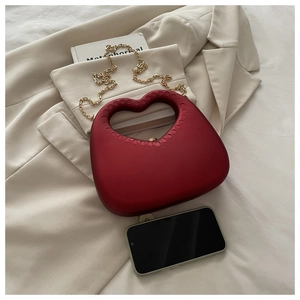 Deep red heart-shaped hard shell clutch bag with gold chain strap and smartphone for scale