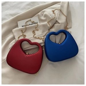 Detail of red and blue heart-shaped acrylic clutch bags with gold chain straps