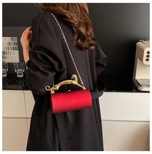 Detail of red cylindrical evening bag featuring a gold leopard handle and chain strap