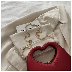 Detail view of heart-shaped clutch bag with matte texture and gold chain strap