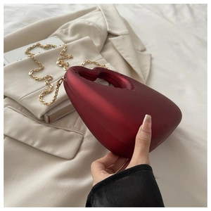 Detail of red heart evening clutch with integrated handle and gold chain strap