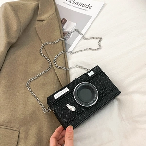 Detail of creative camera shaped crossbody bag in black embossed leather with silver chain