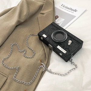 Detail of creative camera-shaped crossbody bag with snake skin texture and metal chain