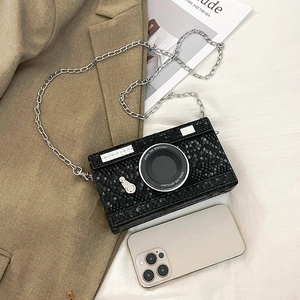 Detail of camera-shaped crossbody bag with snake texture and silver chain strap