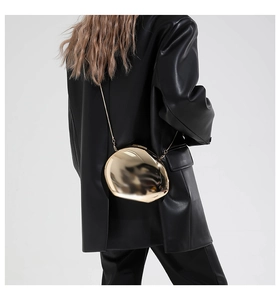 Poliertes goldene Abendtasche in Kieselform mit feiner Kette auf schwarzem Blazer