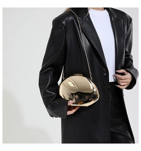 Makrodetail der glänzenden goldenen Muscheltasche mit elegantem Kettenriemen