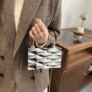 Detalle del bolso caja plateado con acabado de espejo adiamantado y asa de cuentas doradas