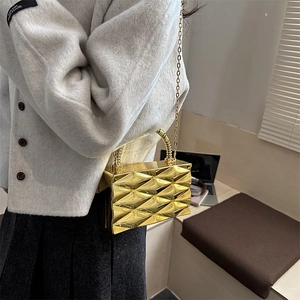 Detalle del bolso bandolera dorado brillante con textura geométrica facetada y cadena