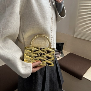 Detalle de bolso de mano metálico dorado con textura en relieve y cadena