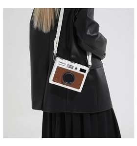 Detail of camera-shaped crossbody bag featuring white and brown leather texture for women