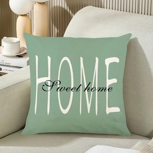 Détail de la housse de coussin vert sauge avec texte HOME Sweet Home sur canapé