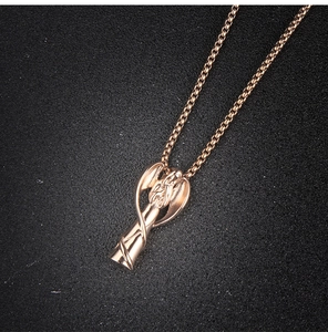 Detail of rose gold angel urn pendant necklace on a textured black surface