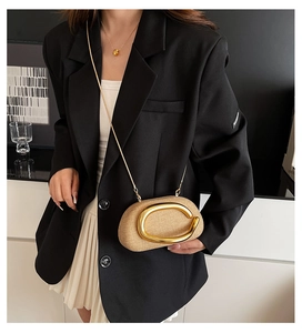 Close-up of beige woven clutch bag with large gold C-handle and fine chain strap