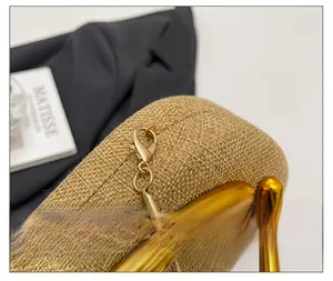 Detail of gold metal clasp and snake chain with textured beige woven fabric on luxury bag