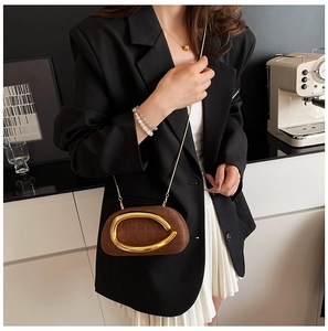 Detail of brown woven crossbody bag with gold ring and chain on a stylish model
