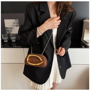 Detail of dark brown textured chain bag with large gold metallic ring on black blazer
