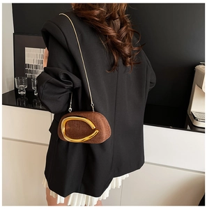 Detailed back view of a brown textured crossbody chain bag on a black blazer