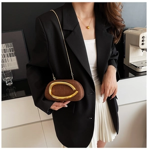 Detail of a brown woven texture shoulder bag with large oval gold metal handle and chain