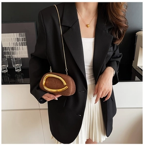 Detailed shot of brown woven clutch bag with large gold metal hardware and chain strap