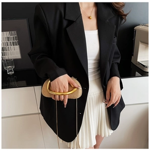 Detail of beige woven clutch with golden circular handle and chain on a stylish model