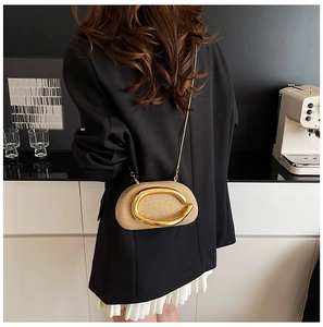 Detail of beige woven evening bag with gold C-shaped buckle and metal chain strap