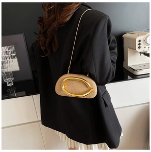 Modern woven evening clutch with large gold C-buckle worn as an elegant crossbody bag