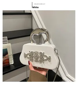 Detail of white evening box bag featuring shimmering rhinestones and silver metal handle